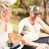 Two people sitting outdoors, one holding a sunday road can