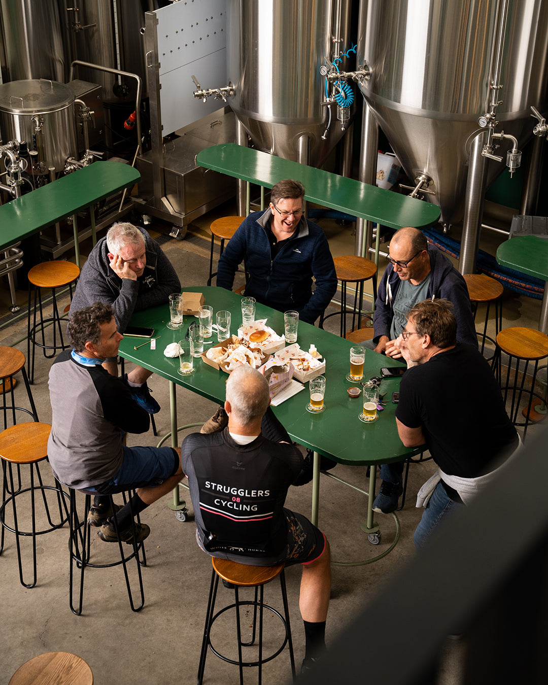 Group of people sitting around a table in the sunday road taproom brewery in kirrawee sutherland shire with beer glasses and food.