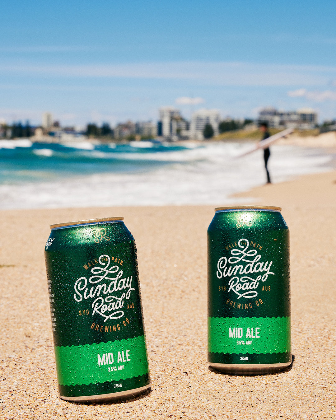 perfect surf beer Sunday Road Brewing Mid Ale on a sandy beach with ocean at wanda beach cronulla