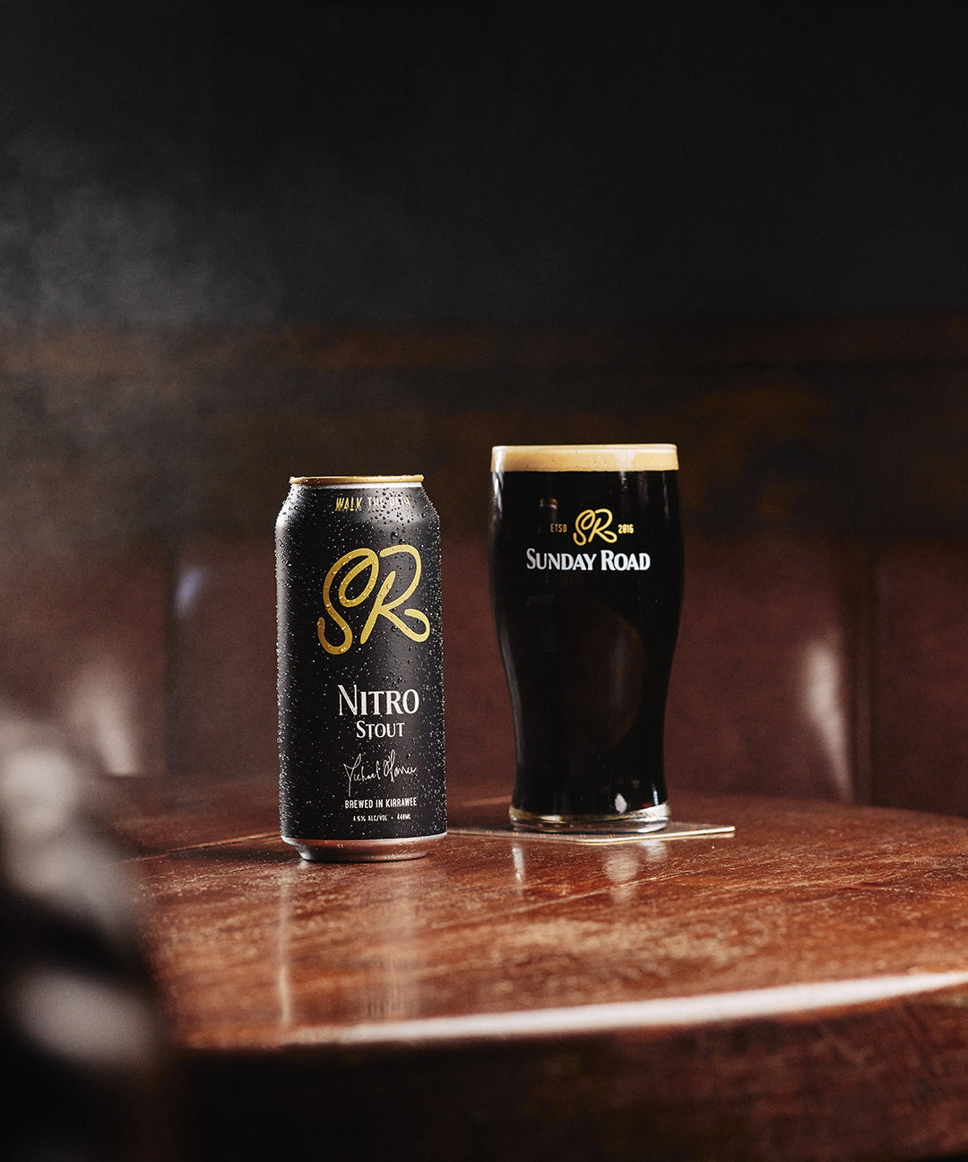 Sunday Road Nitro Stout can and glass on a wooden table with a dark background