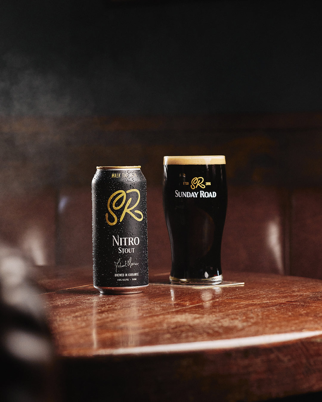 Sunday Road Nitro Stout can and glass on a wooden table with a dark background