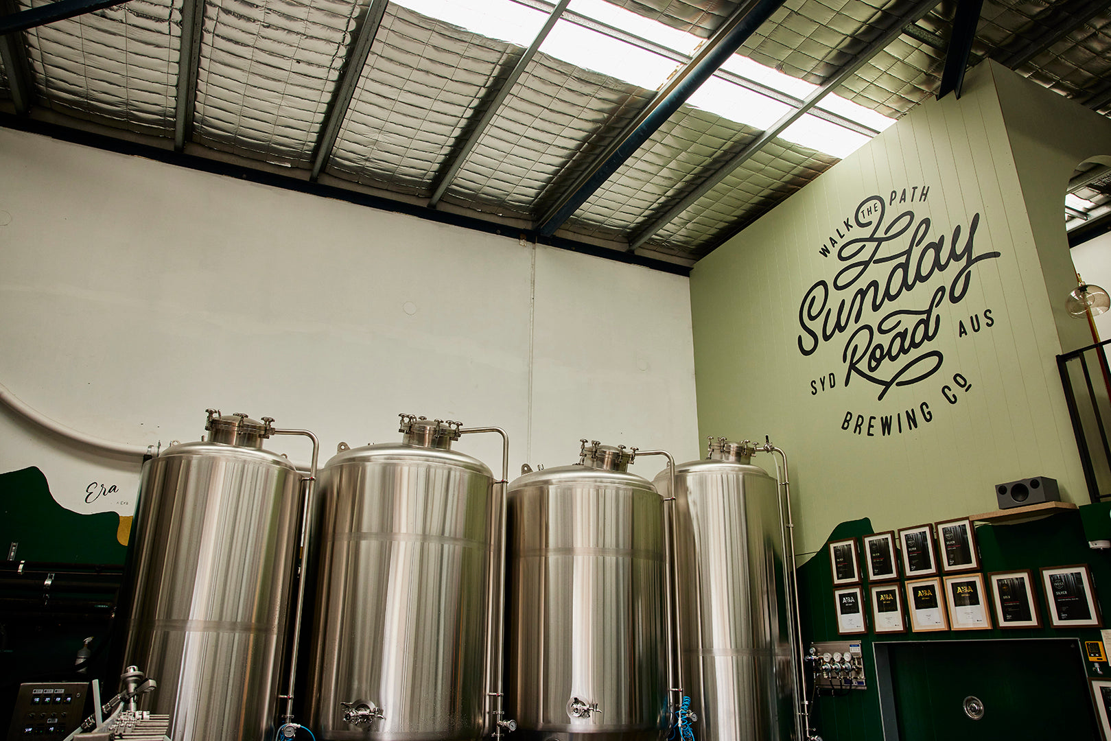 Brewery interior with stainless steel tanks and 'Sunday Road Brewing Co' logo on the wall in sutherland shire brewery