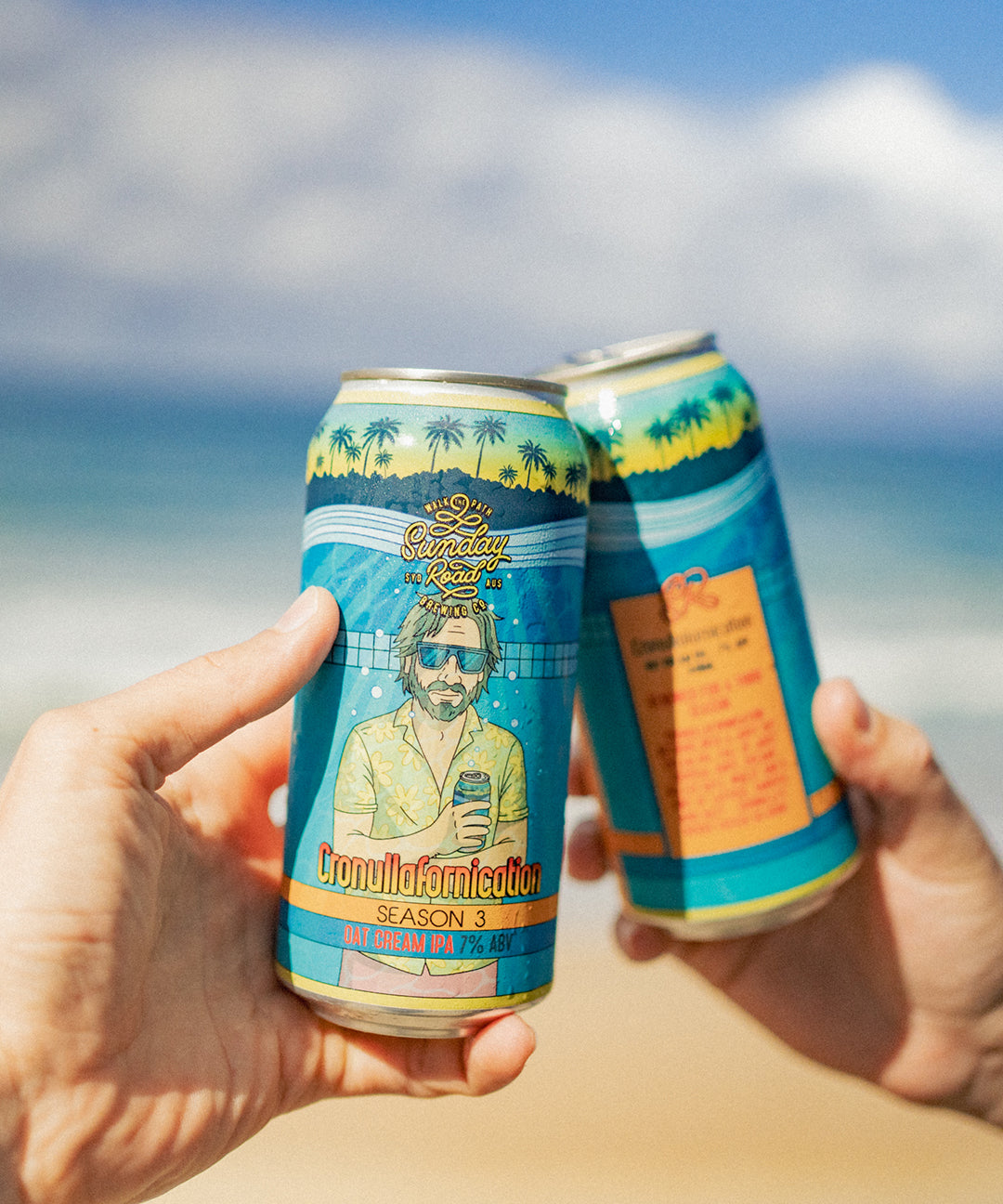 Two cans of Sunday Road Brewing cronullafornication season 3 oat cream ipa beer held up against a beach background